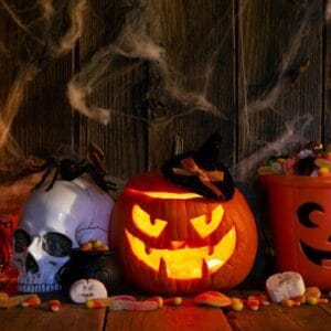 halloween pumpkins with pile of candies on rustic wooden background