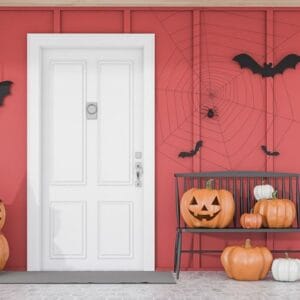 carved,pumpkins,,bats,and,spiders,near,white,front,door,of