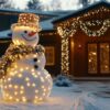 snowman decorated with lights and garlands in a snowy front yard during the holiday season