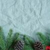 spruce twigs on the green linen crumpled textile background