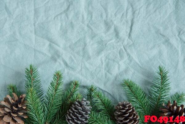 spruce twigs on the green linen crumpled textile background