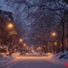 a snowy street with a few cars parked on the side