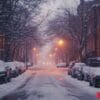 a snowy street with cars parked on both sides