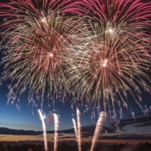 colorful fireworks lighting up the sky with large bursts, silhou