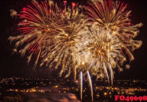 golden and red fireworks spreading across the sky, with city lig