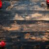 a single red rose with green leaves placed on a rustic wooden table in soft lighting