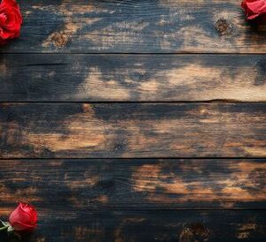 a single red rose with green leaves placed on a rustic wooden table in soft lighting