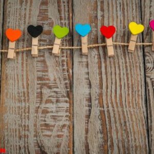 red paper heart hanging on wood background .