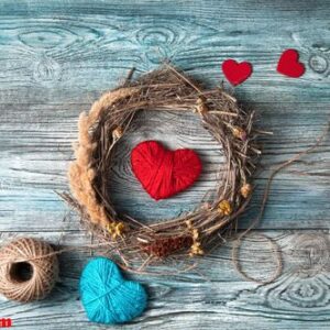 red and blue hearts and a wreath of natural branches and dry grass on a gray blue wooden background.